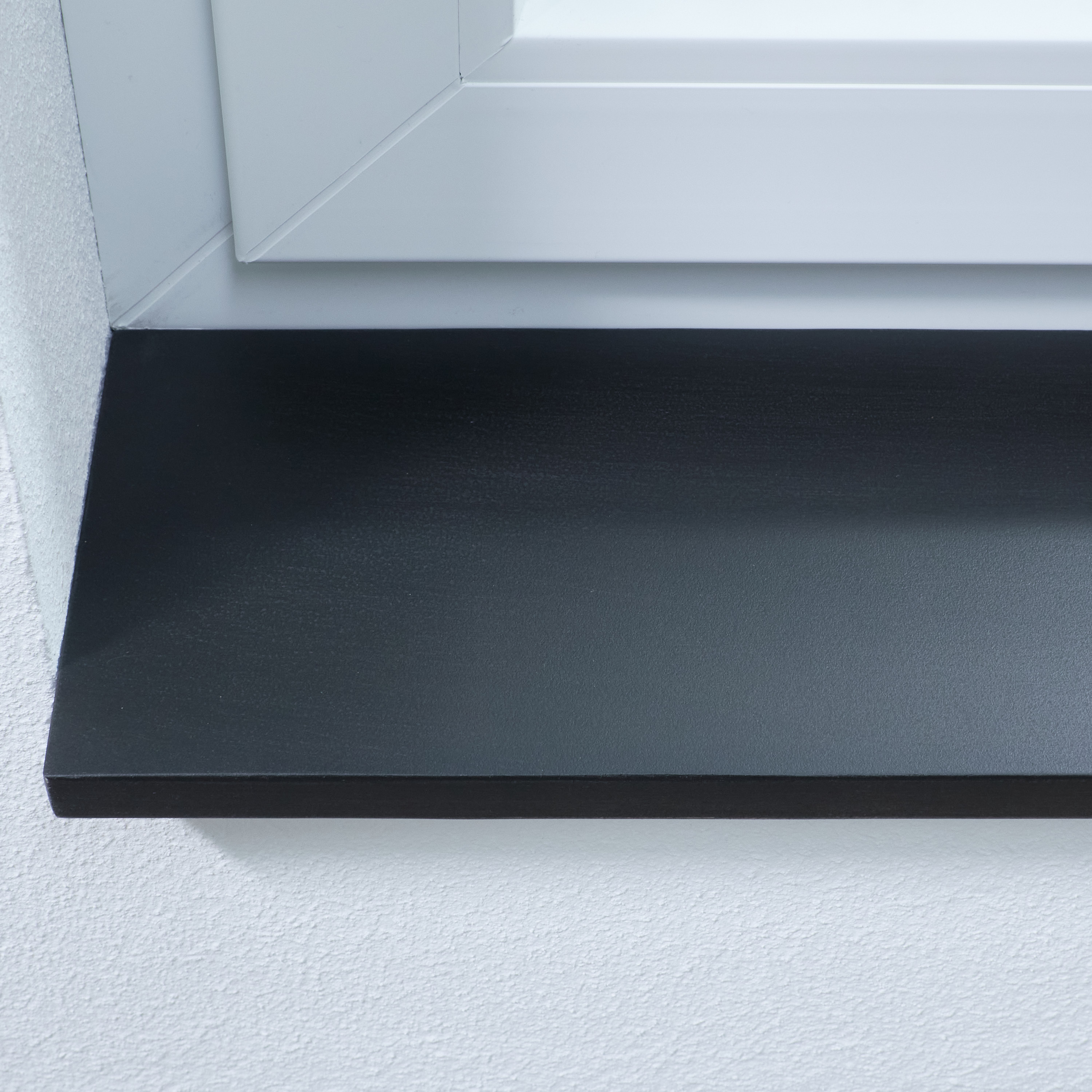 Alféizar negro de madera maciza, primer plano del canto frontal y la superficie bajo el marco blanco de la ventana