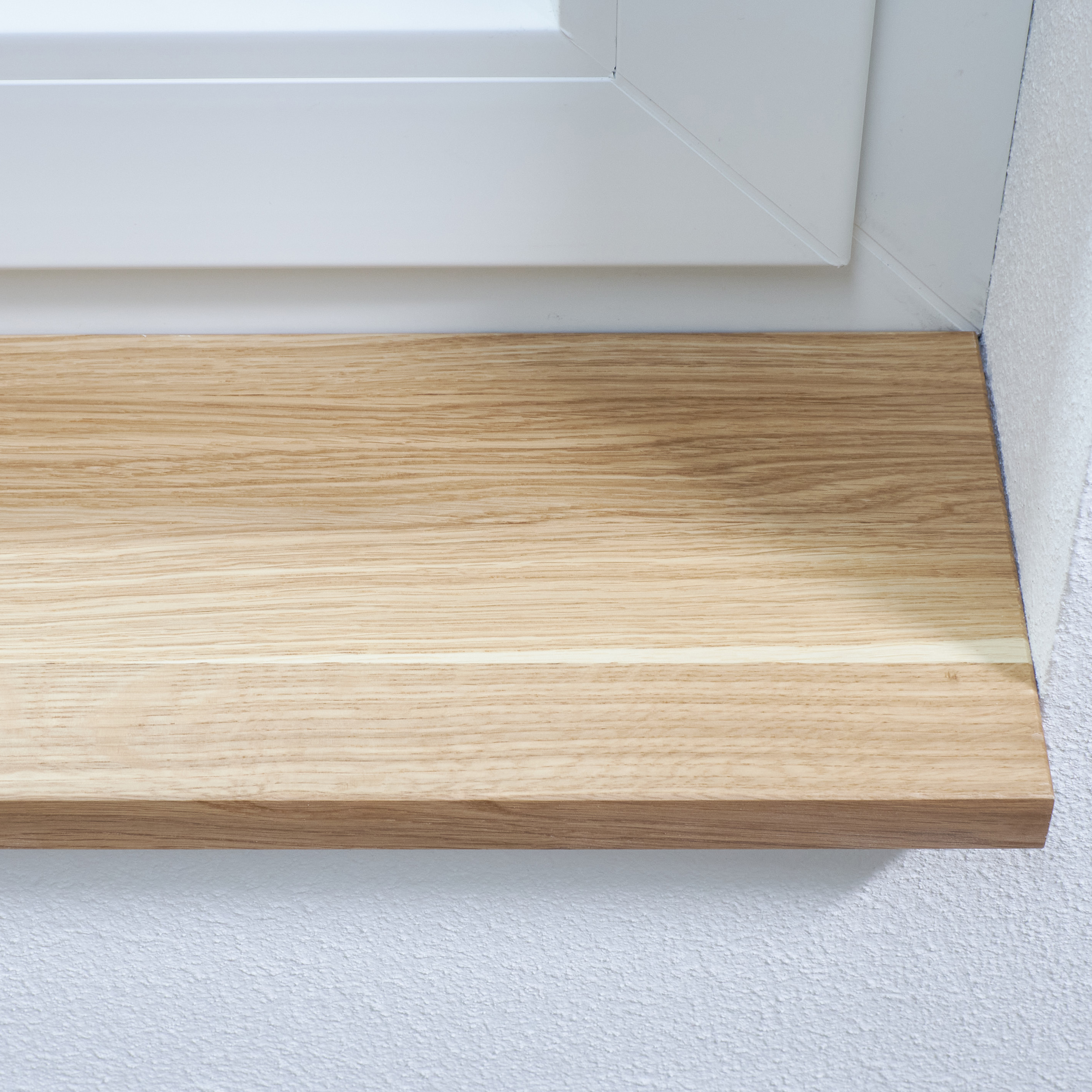 Alféizar de roble macizo natural, instalado bajo el marco blanco de la ventana, primer plano del veteado