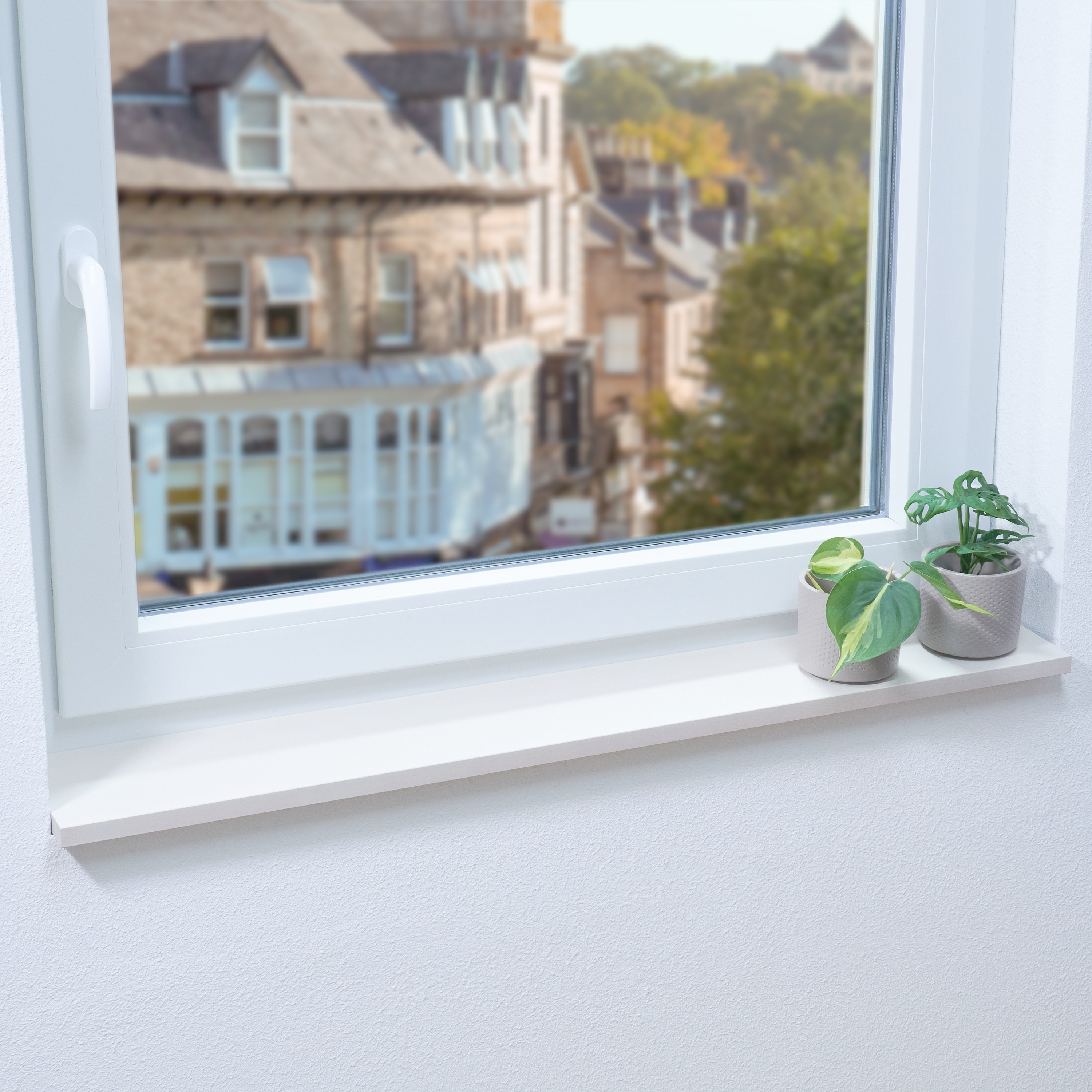 Alféizar de madera lacado en blanco en ventana blanca con dos plantas pequeñas, vistas a casas de ciudad y árboles