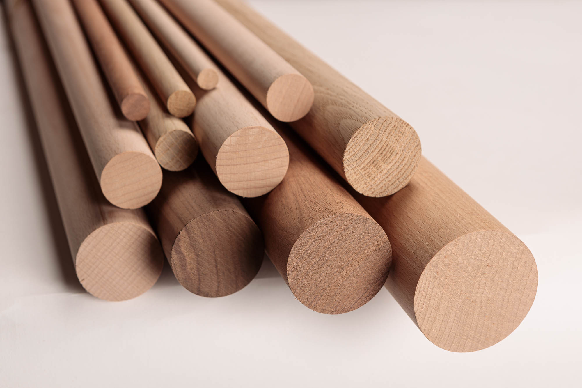 Barras redondas de madera de distintos diámetros y maderas, agrupadas en haz y tumbadas con las testas visibles