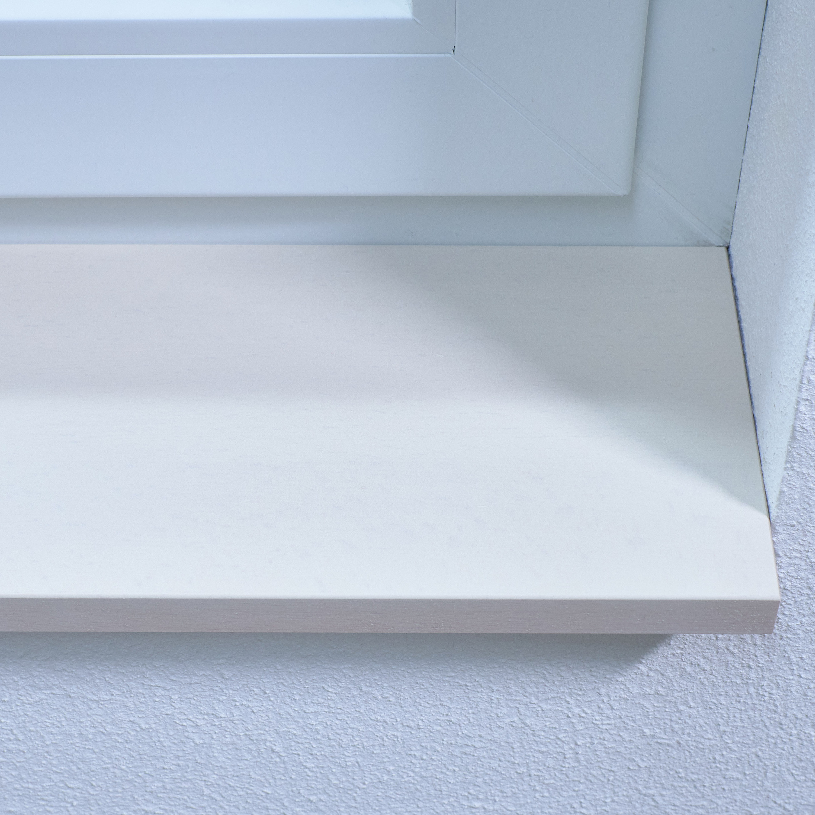 Alféizar de haya teñido de blanco, primer plano del canto delantero del alféizar blanco junto al derrame blanco