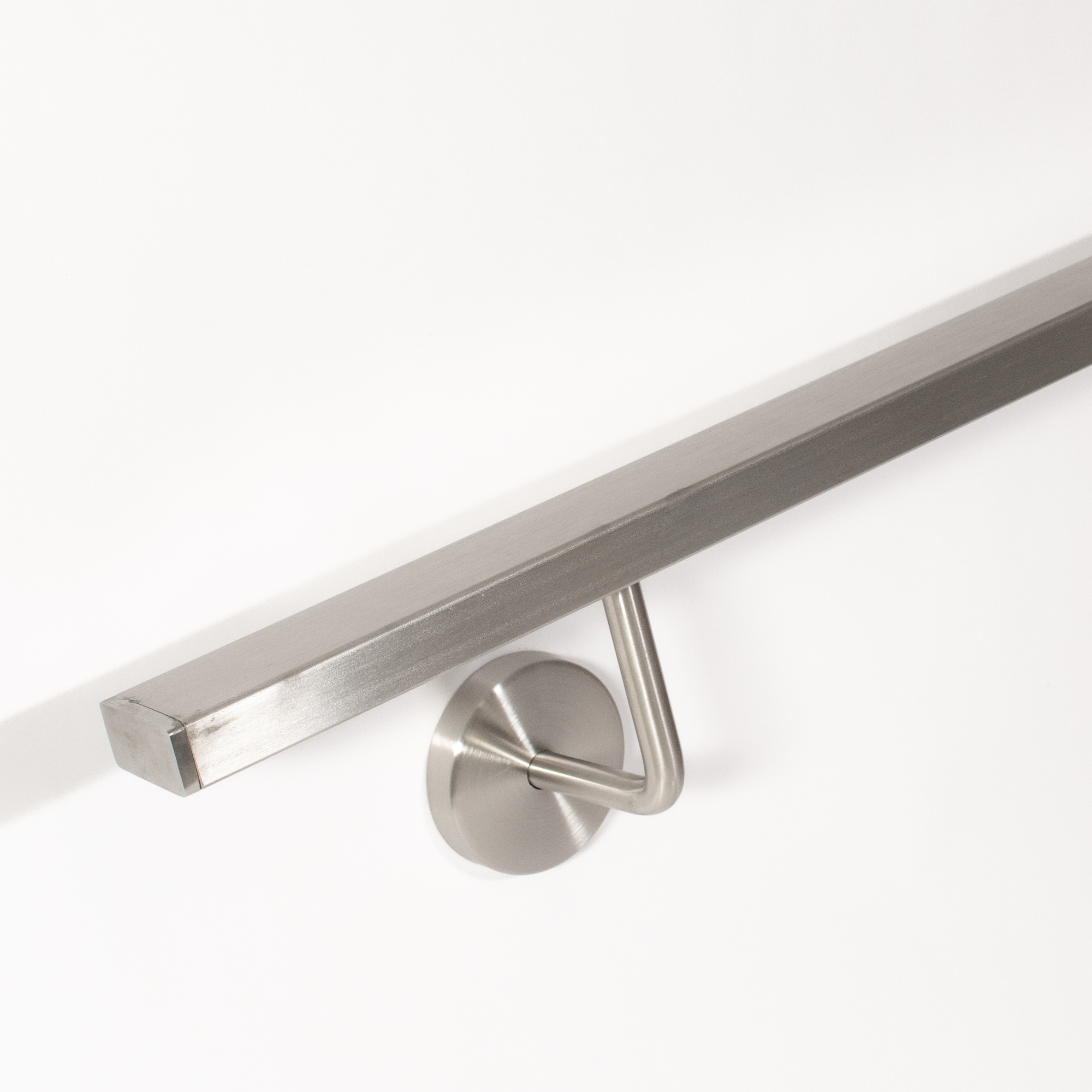 Pasamanos rectangular de acero inoxidable con soporte de pared curvado, vista oblicua desde abajo del extremo en pared blanca