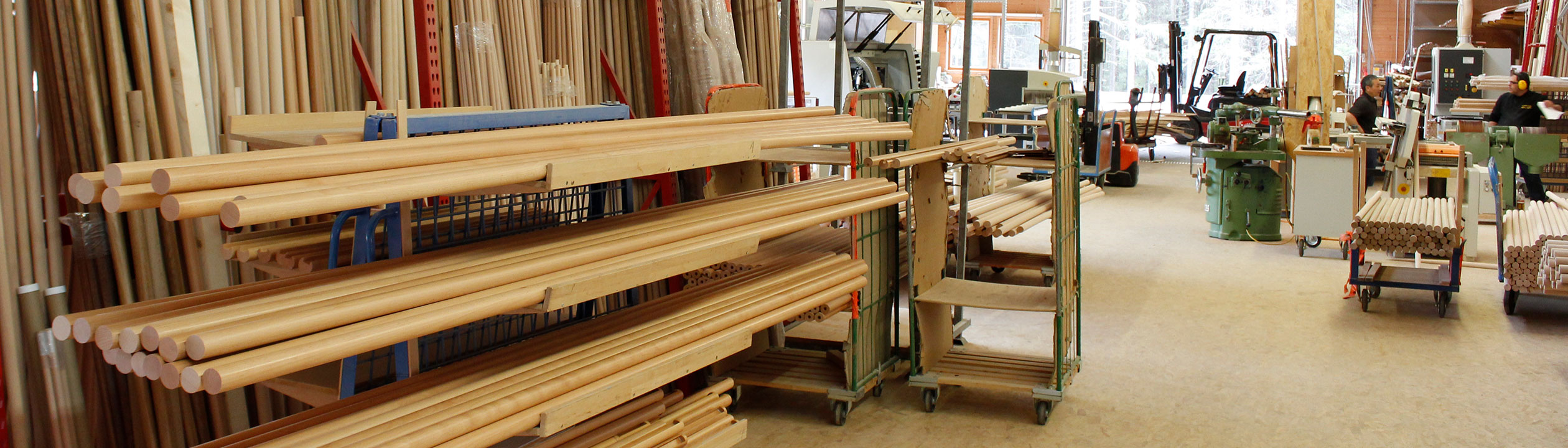 Fabricación de pasamanos: almacén con pasamanos de madera claros y barras redondas en carros en el taller, formato banner
