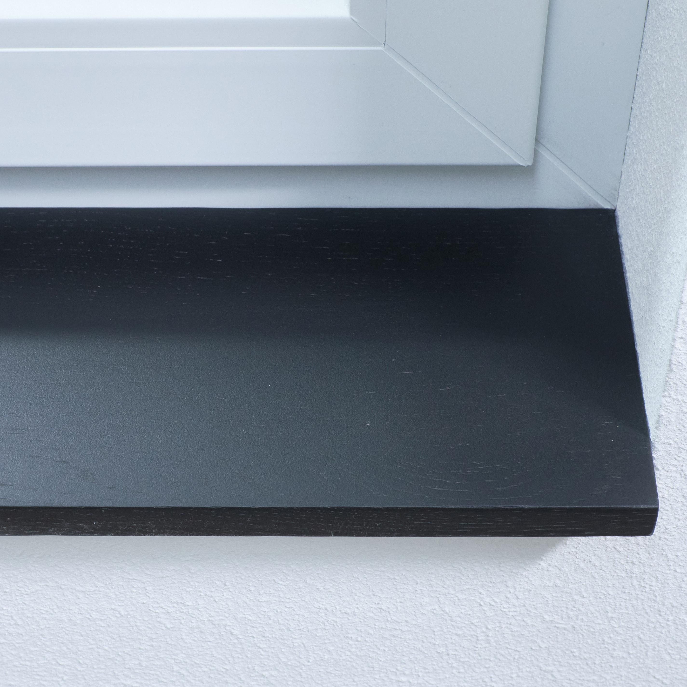Alféizar de roble teñido de negro, primer plano del canto delantero con ligera textura de madera en derrame blanco