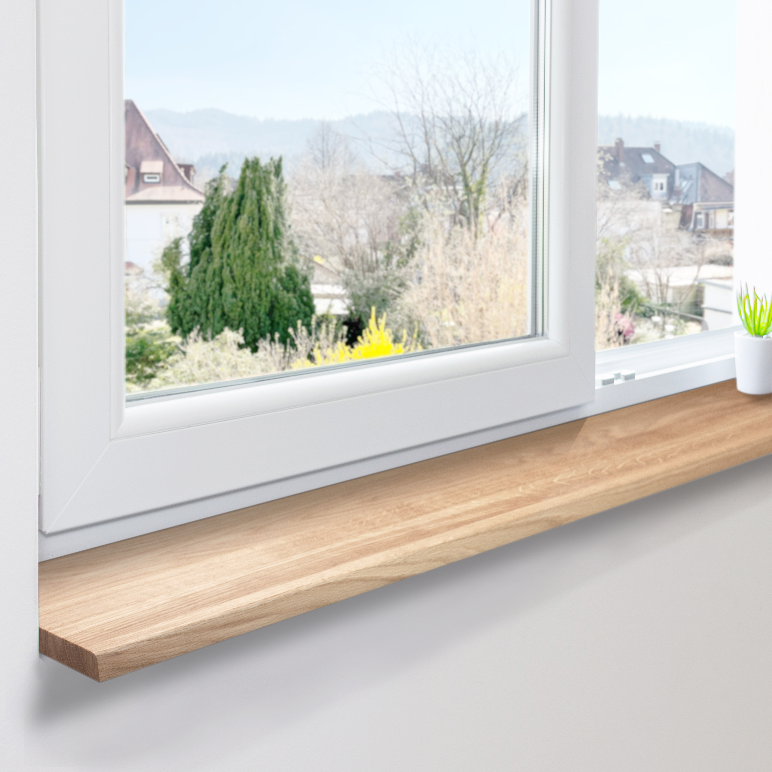 Alféizar de roble natural montado en ventana blanca de PVC, lamas continuas, vista a casas y árboles