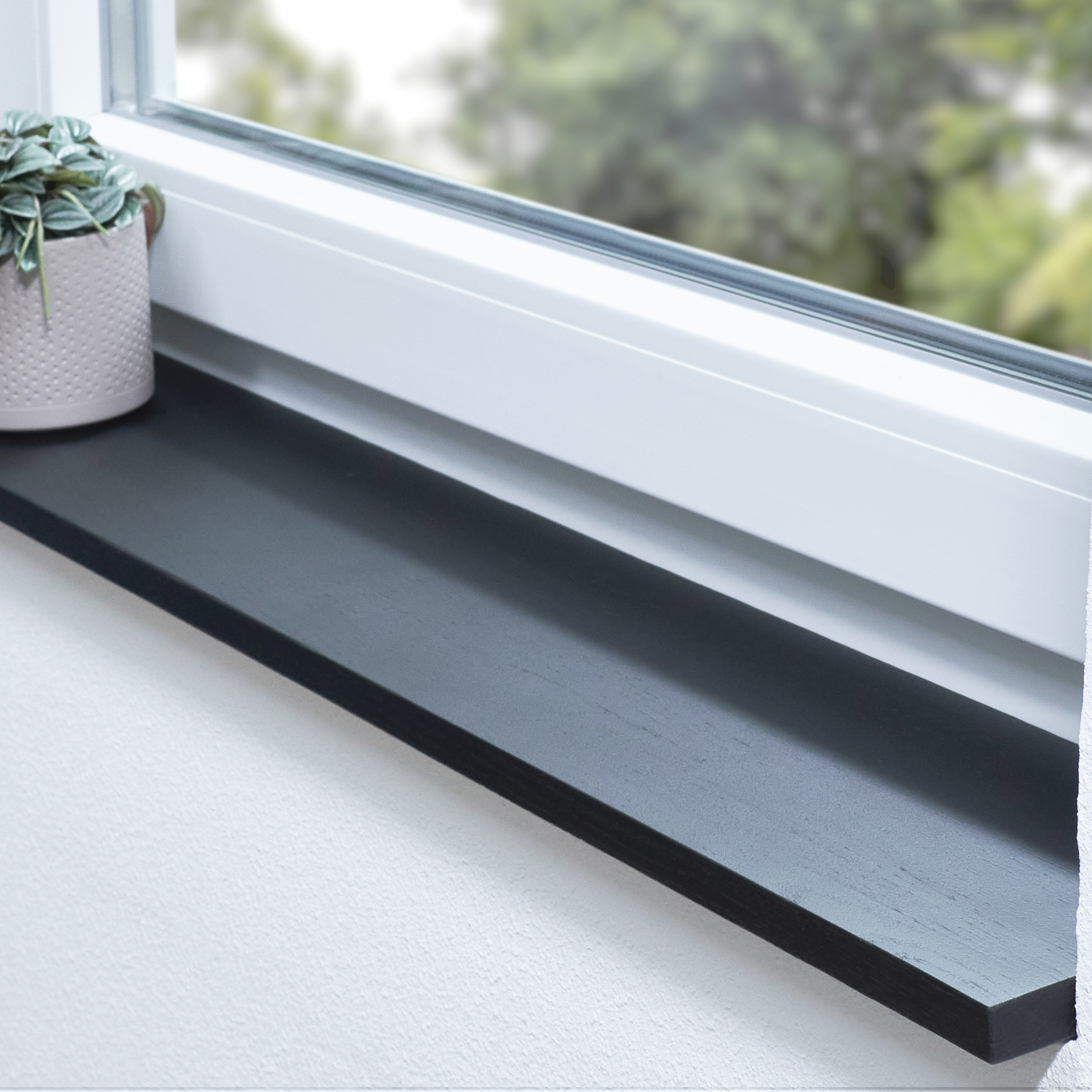 Alféizar de roble teñido de negro, con unión dentada, en derrame de ventana blanco con planta en maceta y vista al verde