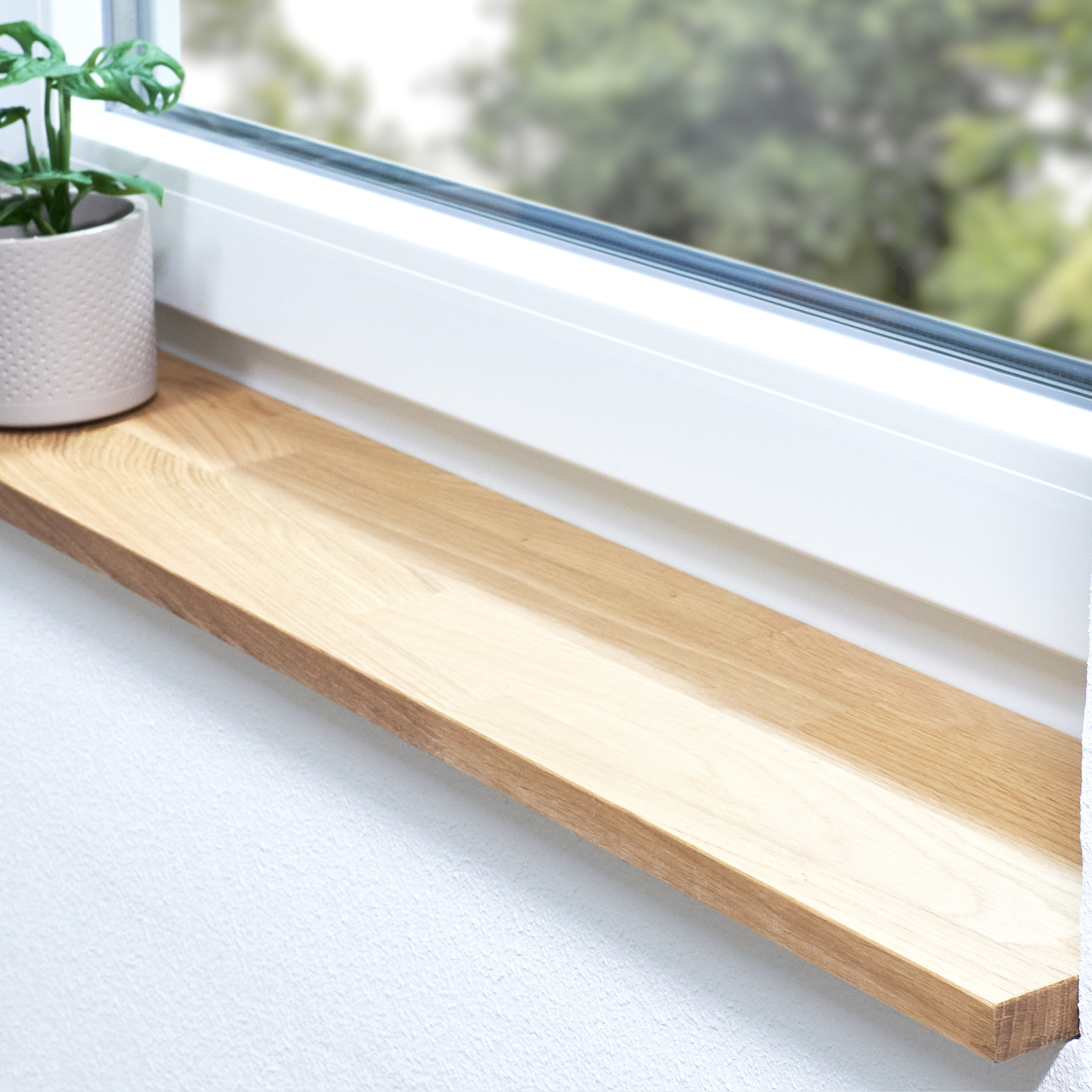 Alféizar de roble natural, con unión dentada, en derrame de ventana blanco con planta en maceta y vista al verde